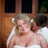 Bride smiles as groom kisses her on her neck
